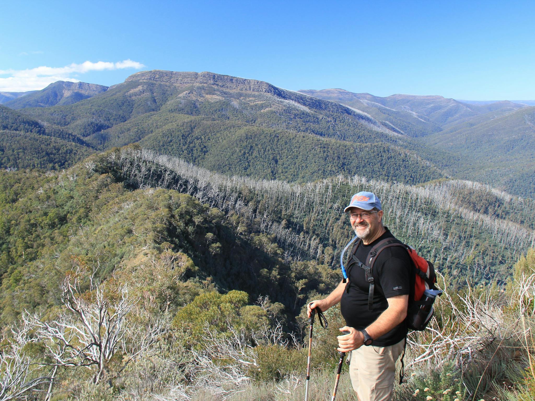A hiker with a brilliant view of The Bluff and Mt Eadley Stoney, and The Crosscut Saw on the horizon