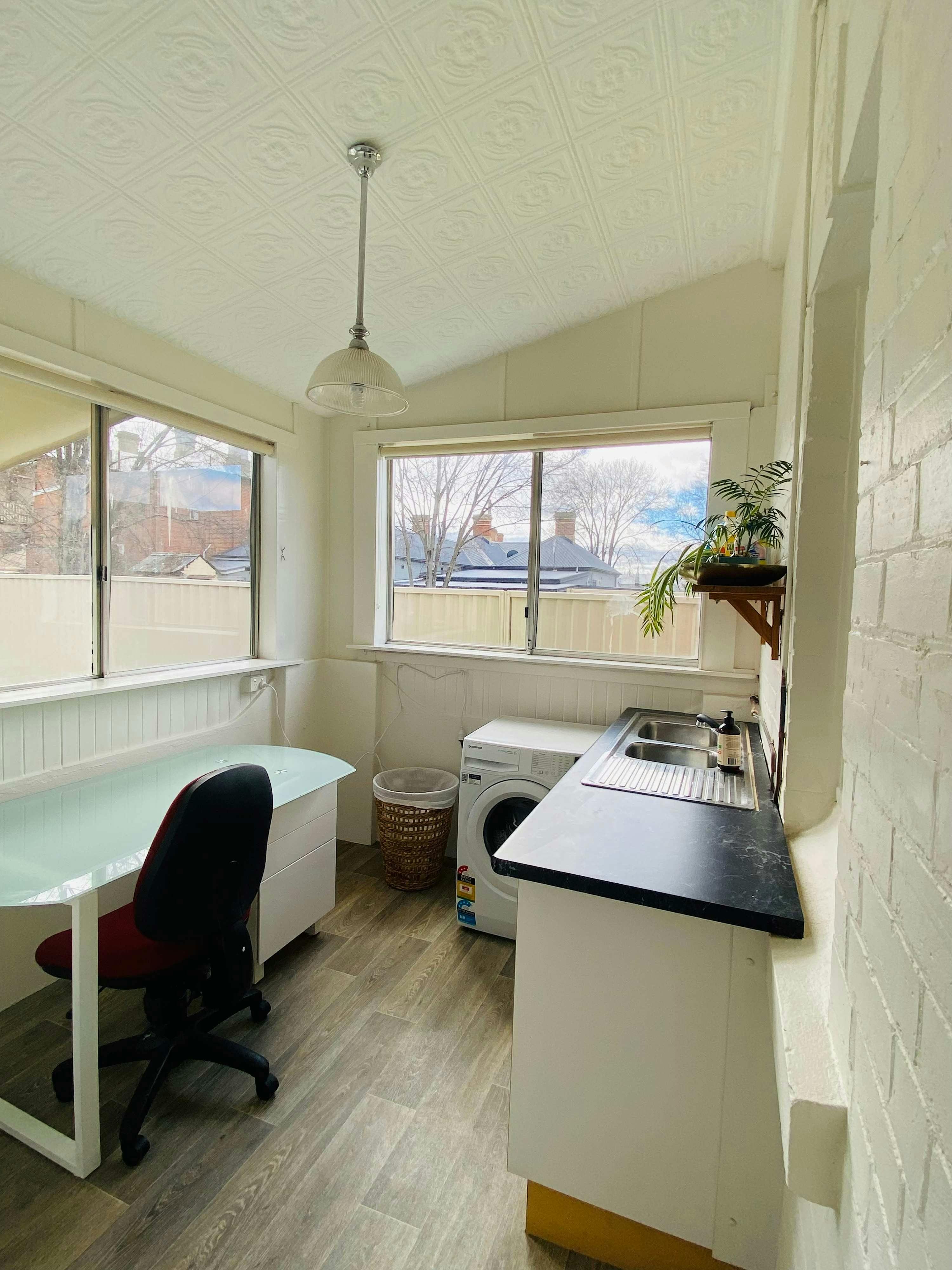 Laundry with washing machine, windows and desk