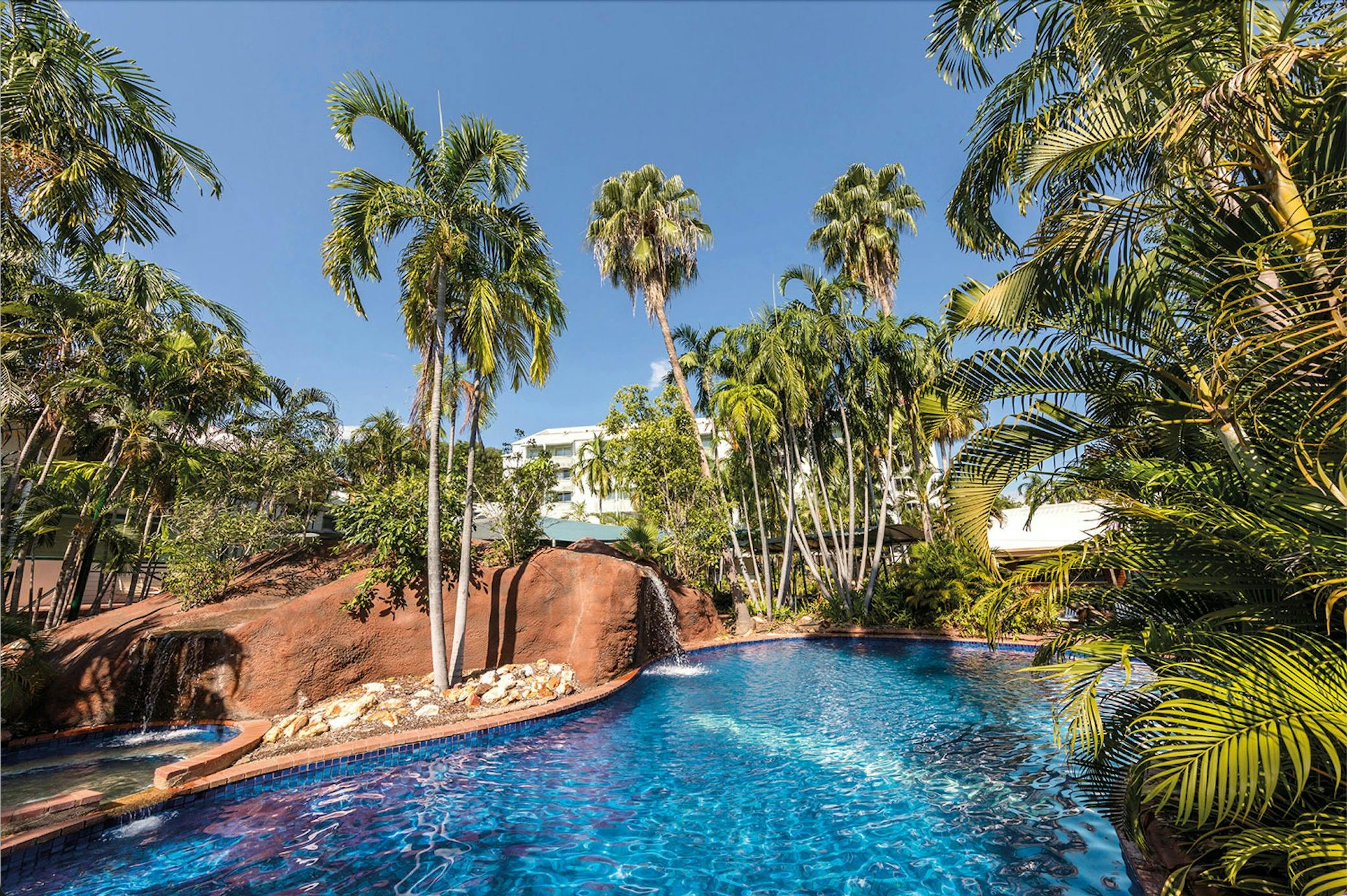 Resort style outdoor pool surrounded by tropical gardens.
