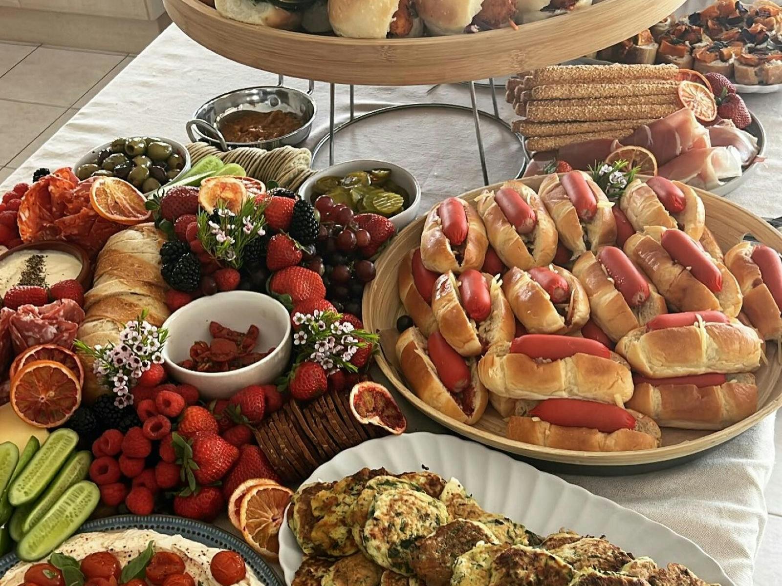 Food Platter including fruit, hot dogs, fritters, biscuits, meats, breadrolls