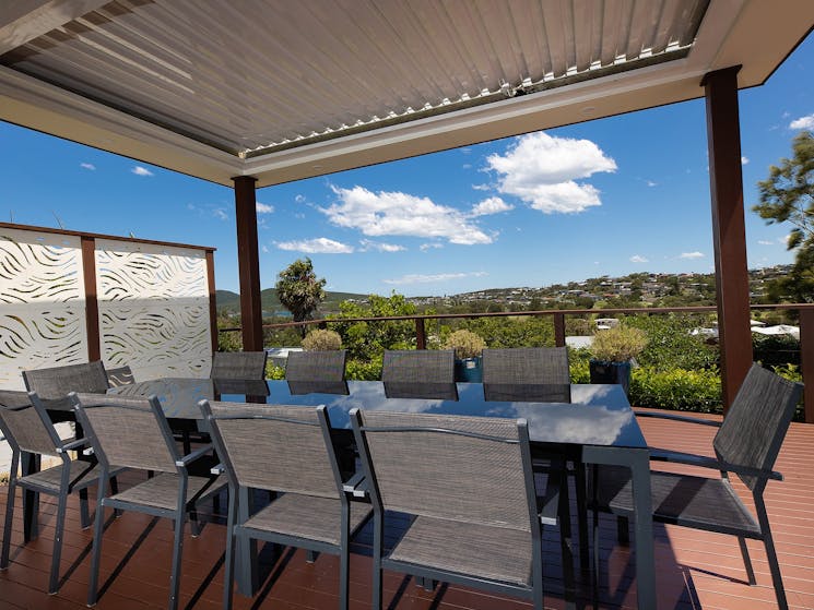 Outdoor entertaining deck with views of the coastline, a barbecue and 10 seater dining setting