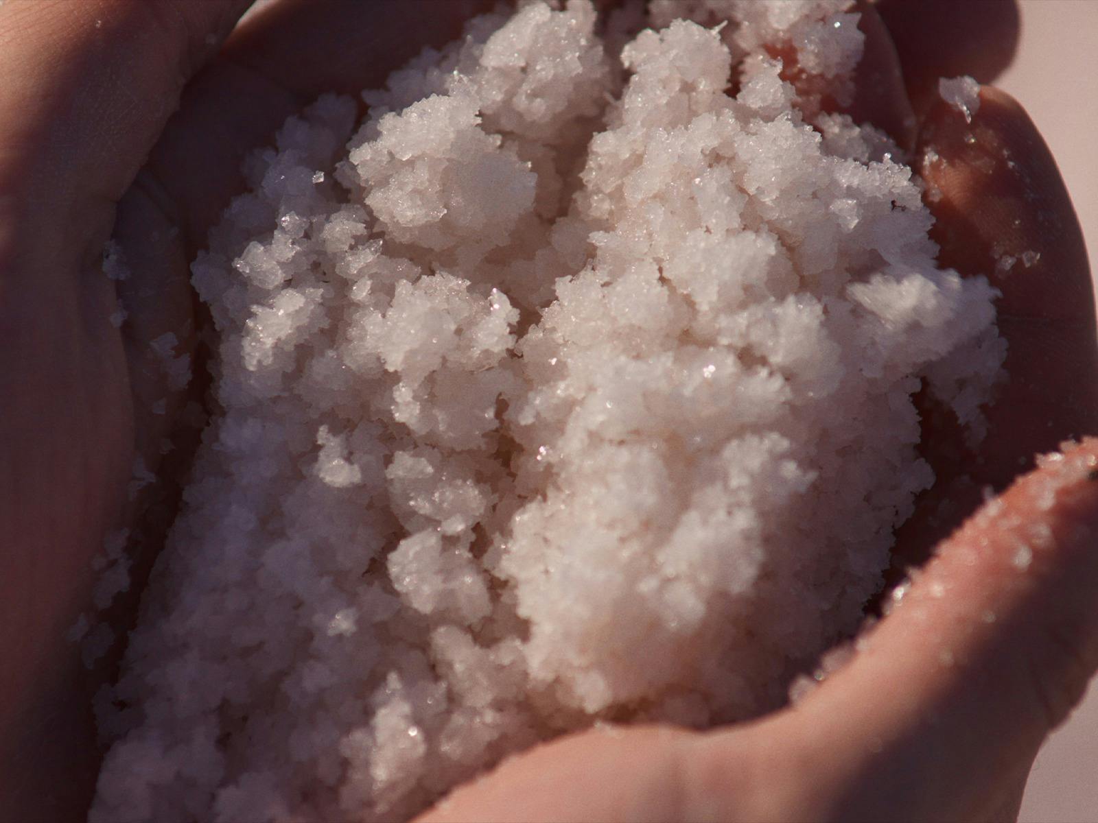 Hands holding a mound of sparkling white crystals.