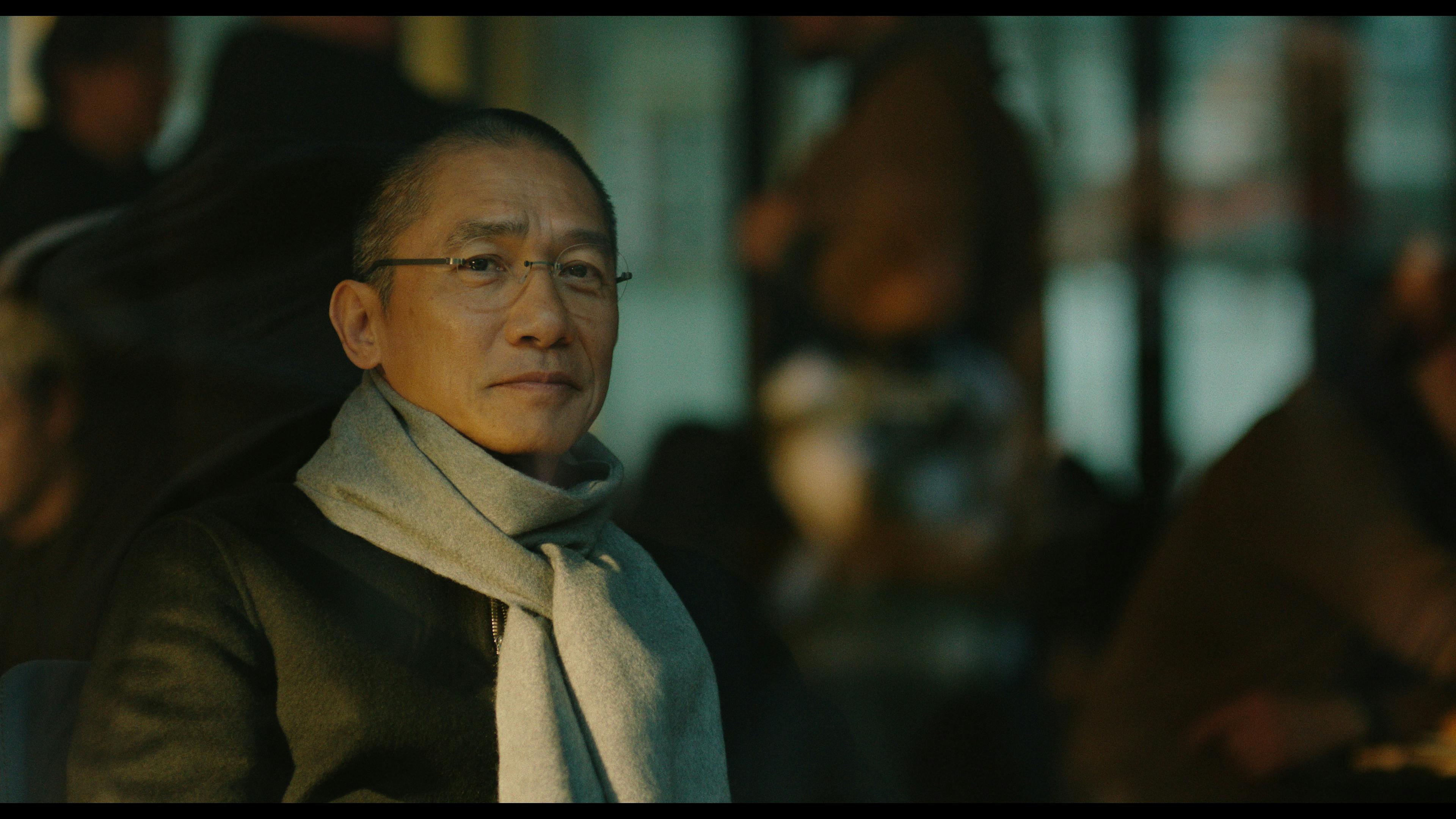 A man in a scarf stares serenely.