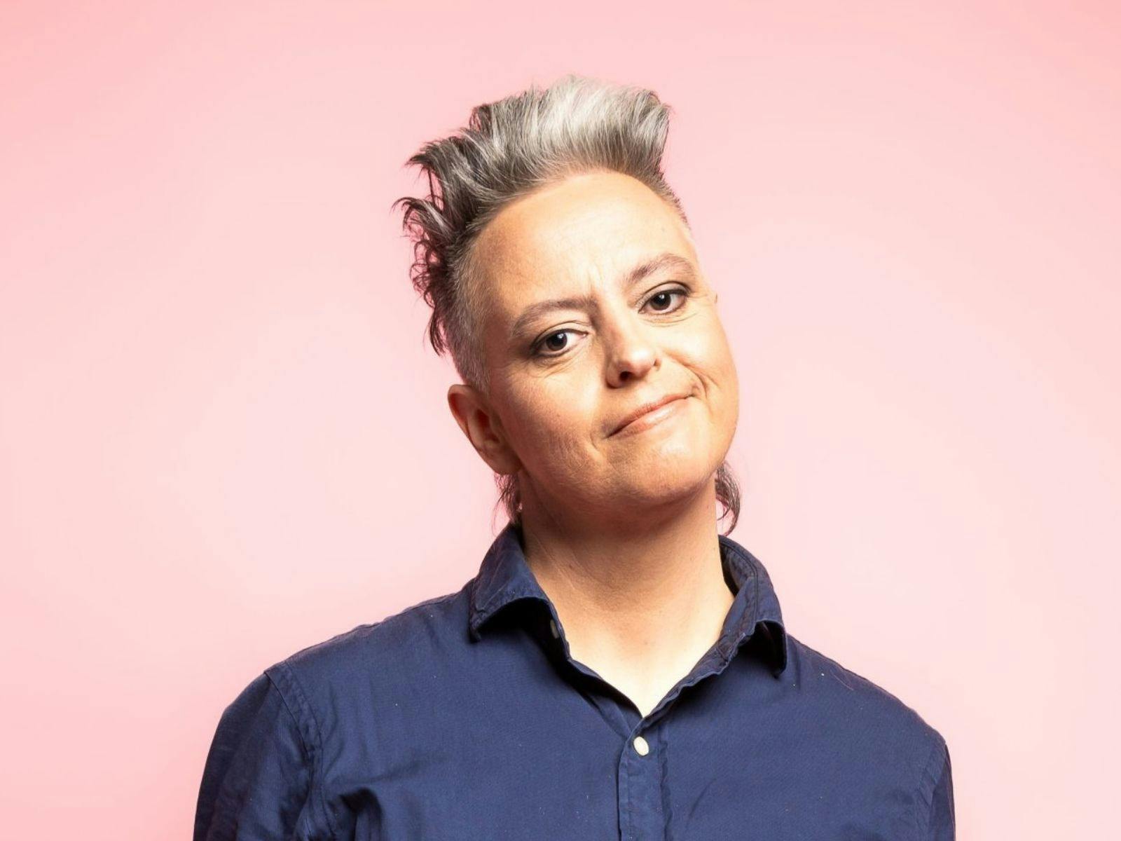 A middle aged woman wearing navy blue shirt with grey hair.