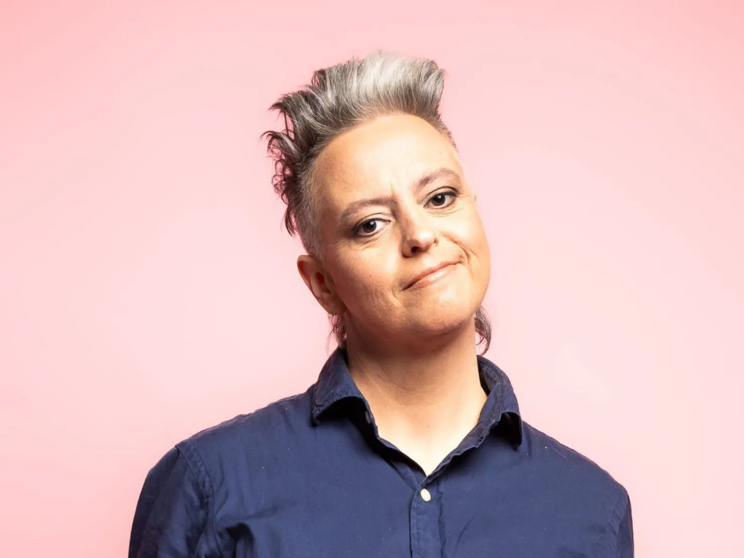 A middle aged woman wearing navy blue shirt with grey hair.