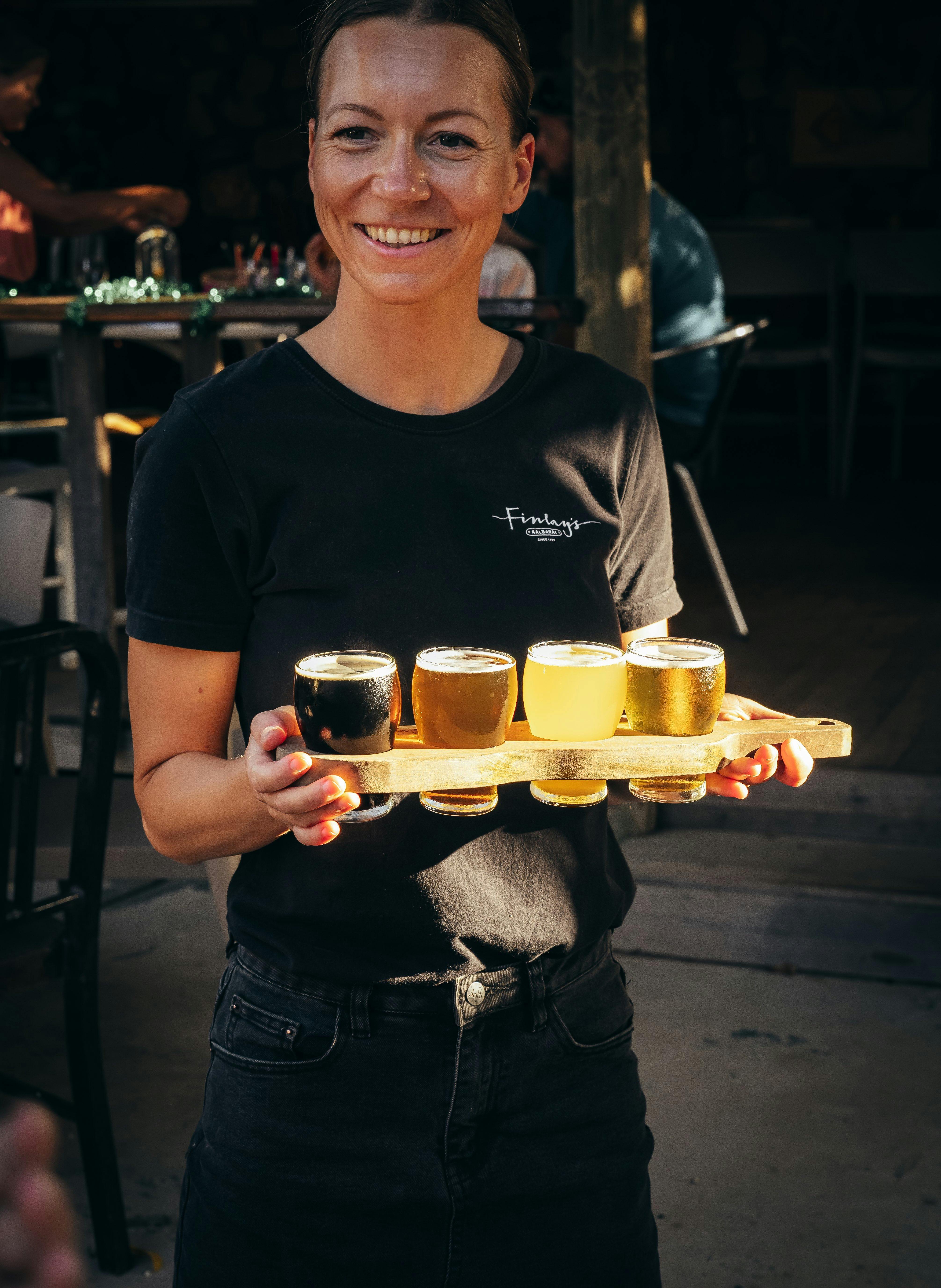 A staff member carrying a beer tasting paddle
