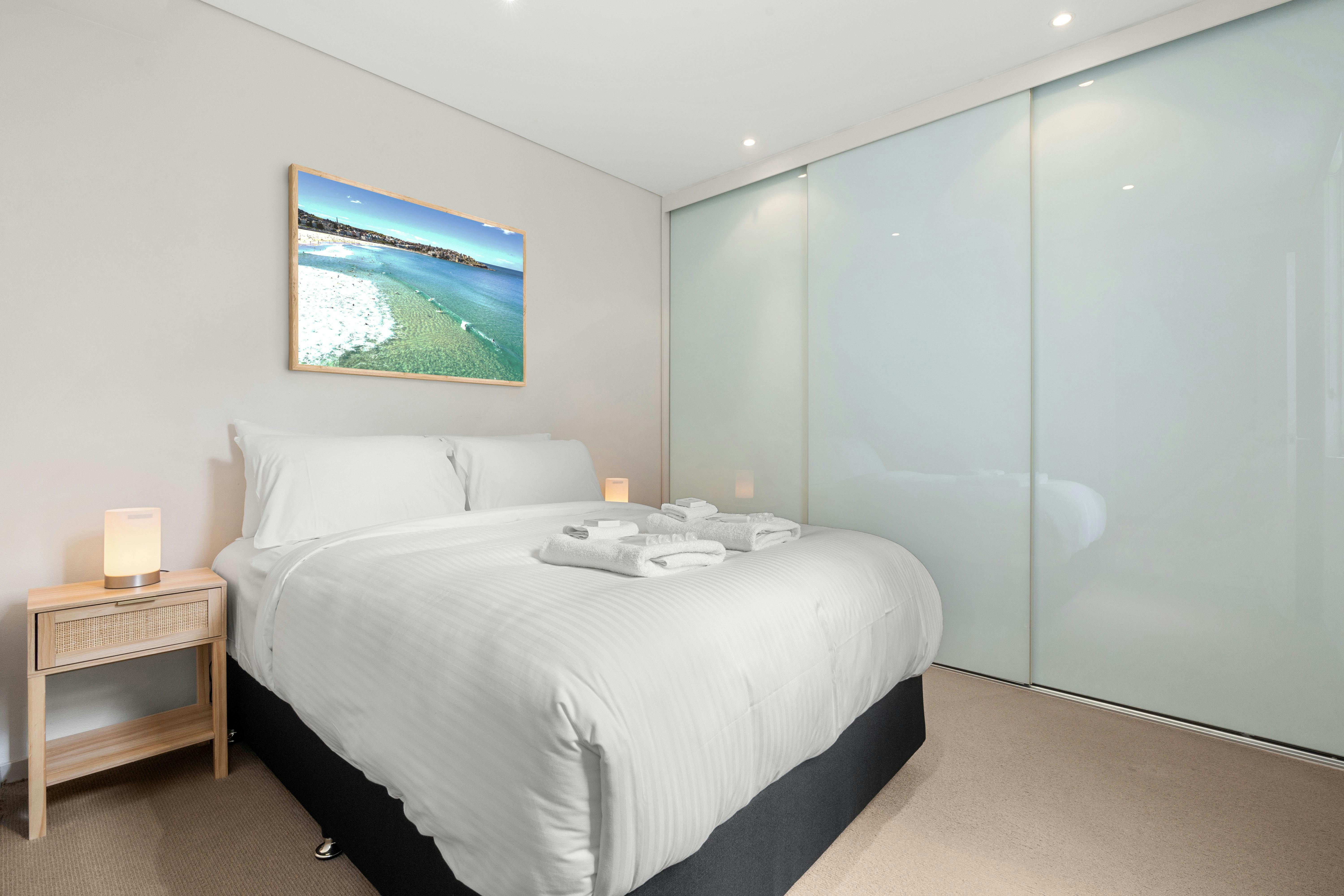 Comfortable bedroom with a beach view painting and clean lines.