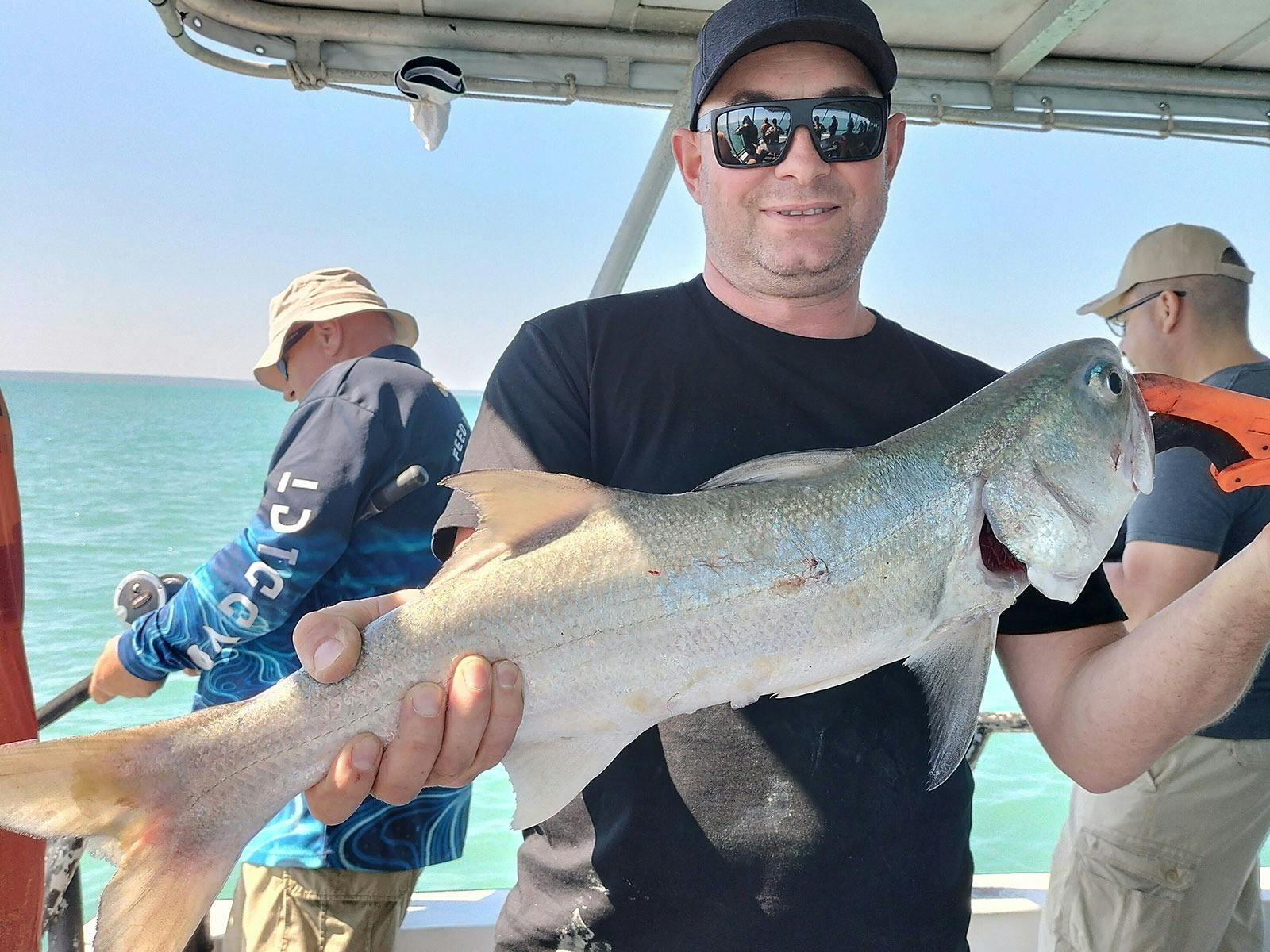A man holding a fish on a Darwin Red Devil Charter.