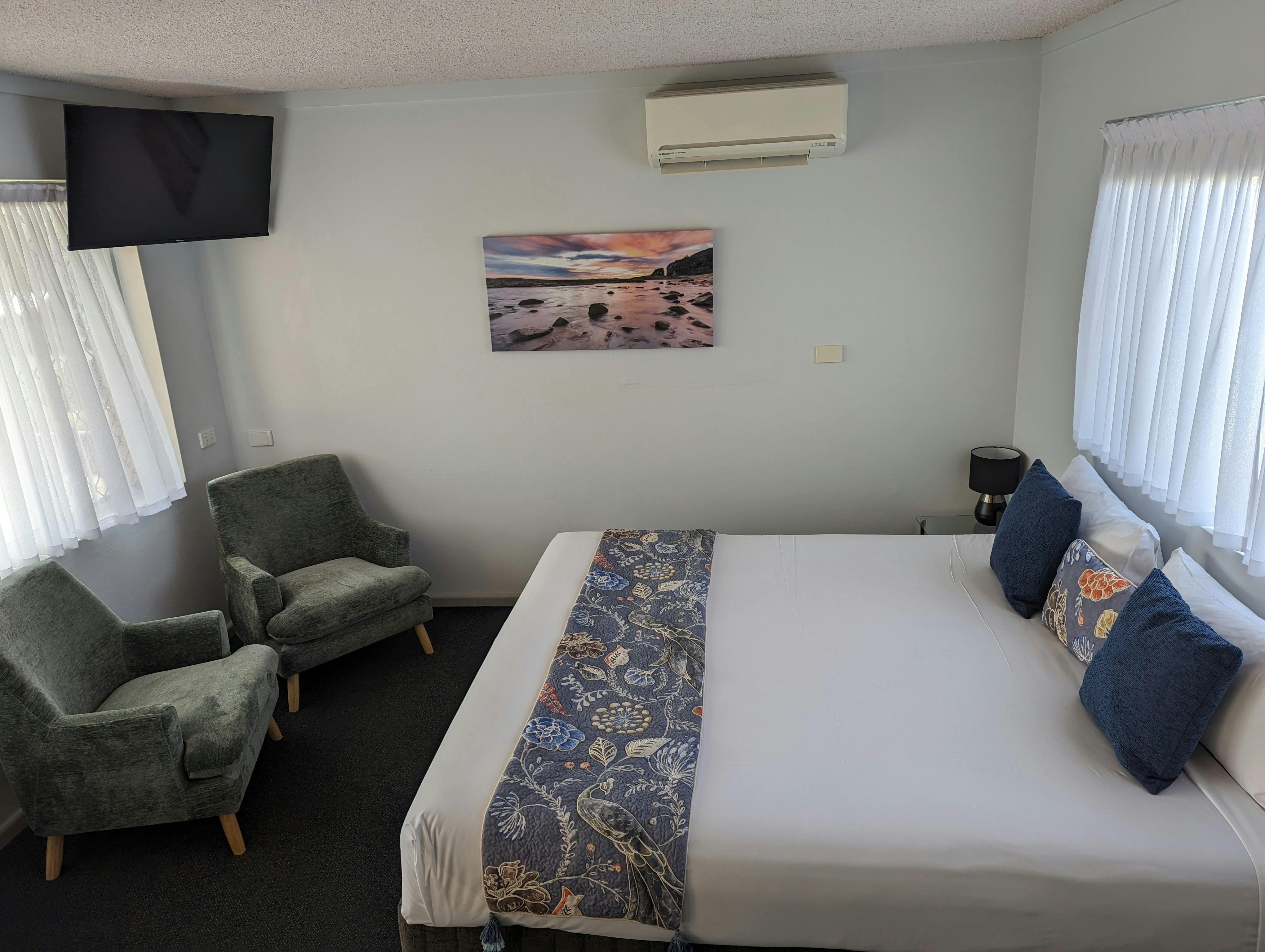 King motel room. One large king bed and 2 green occasional chairs