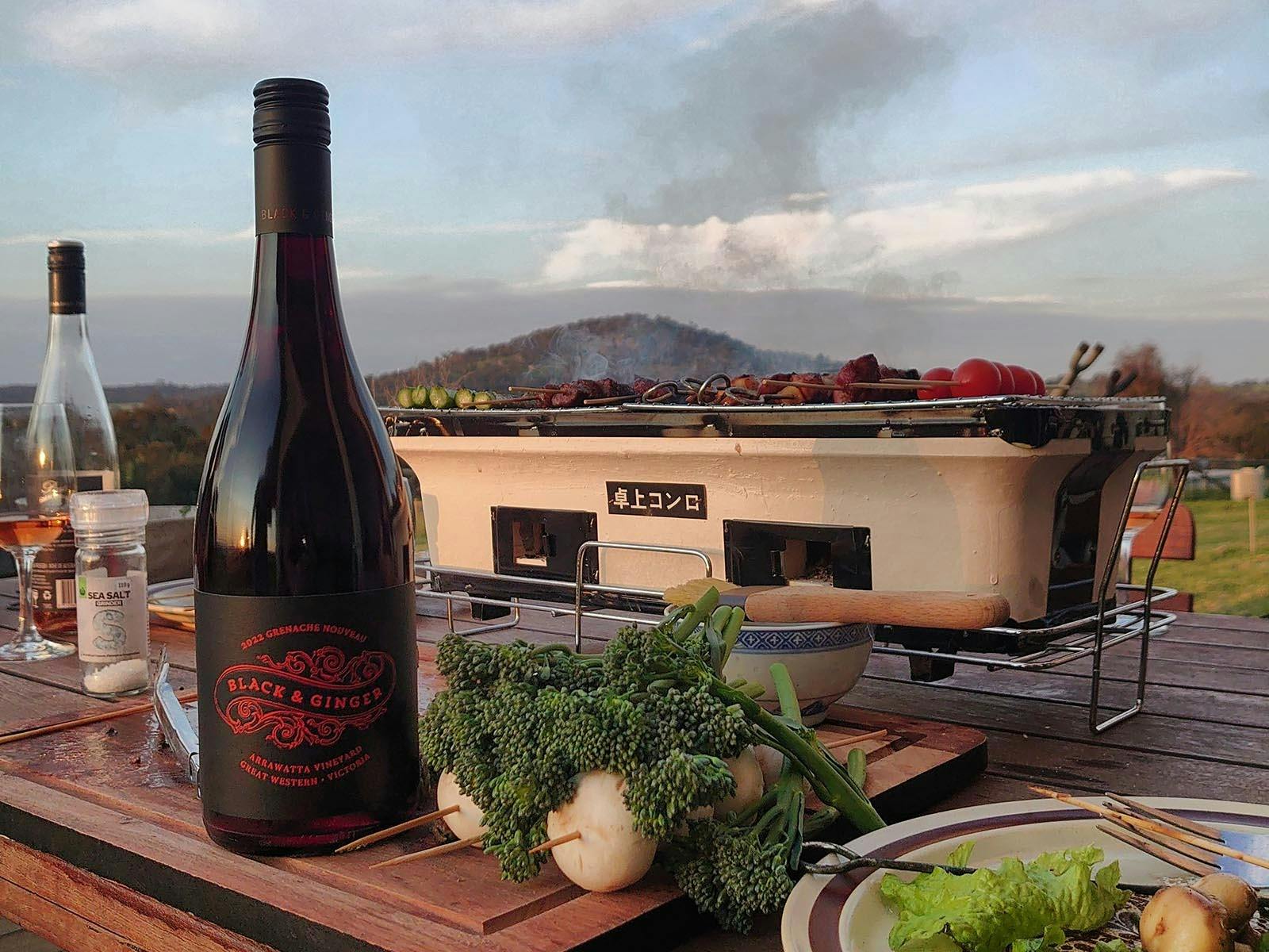 A bottle of Black & Ginger Grenache with a hibachi grill cooking