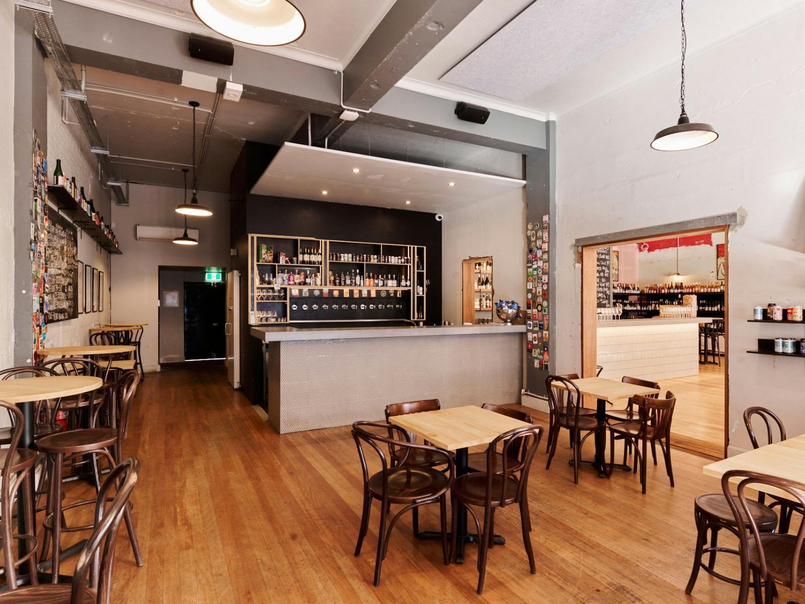 Wide view of room with bar, tables and chairs, no people