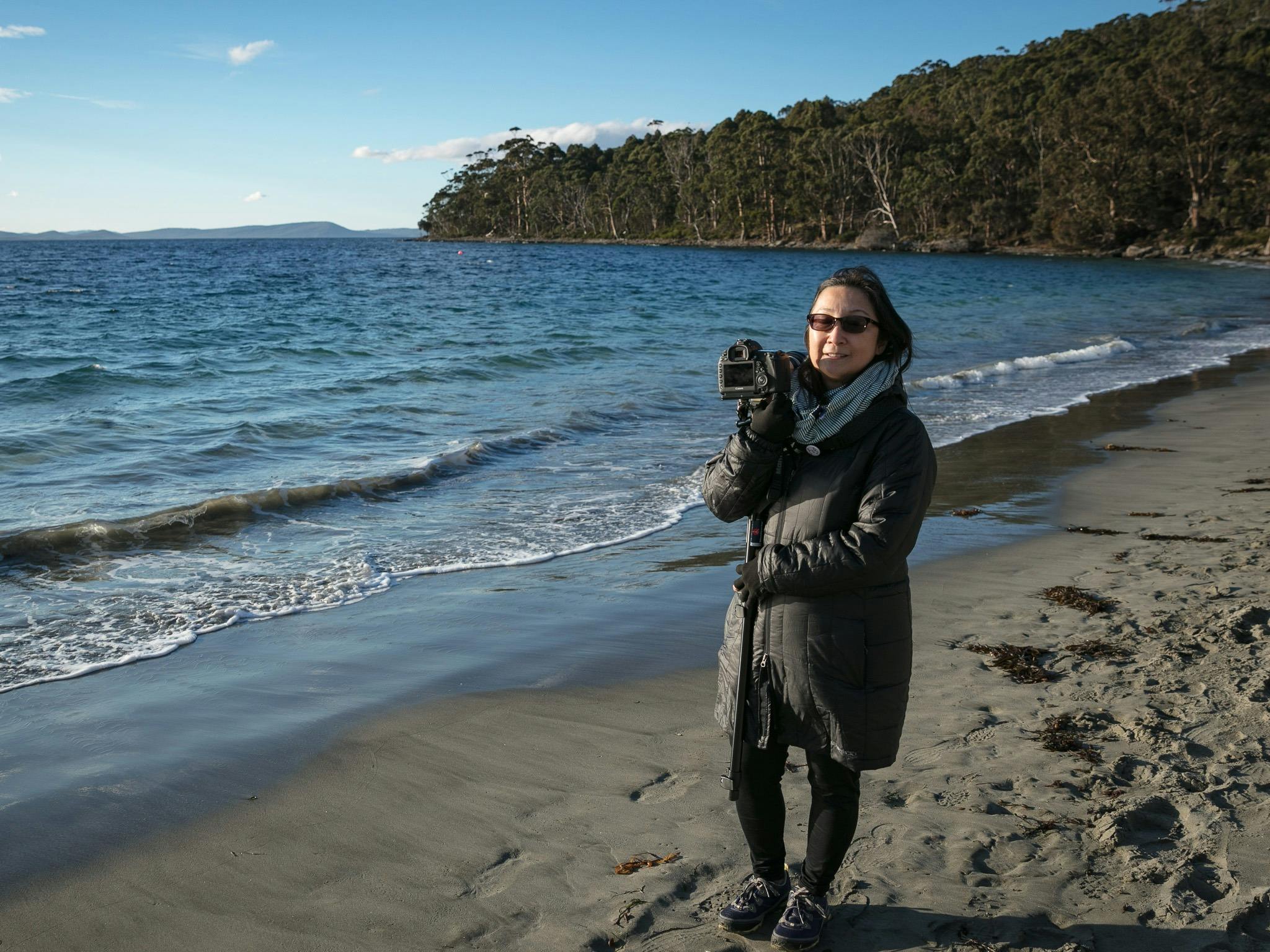 Guest on private Shutterbug Walkabouts tour standing on beach with water in background