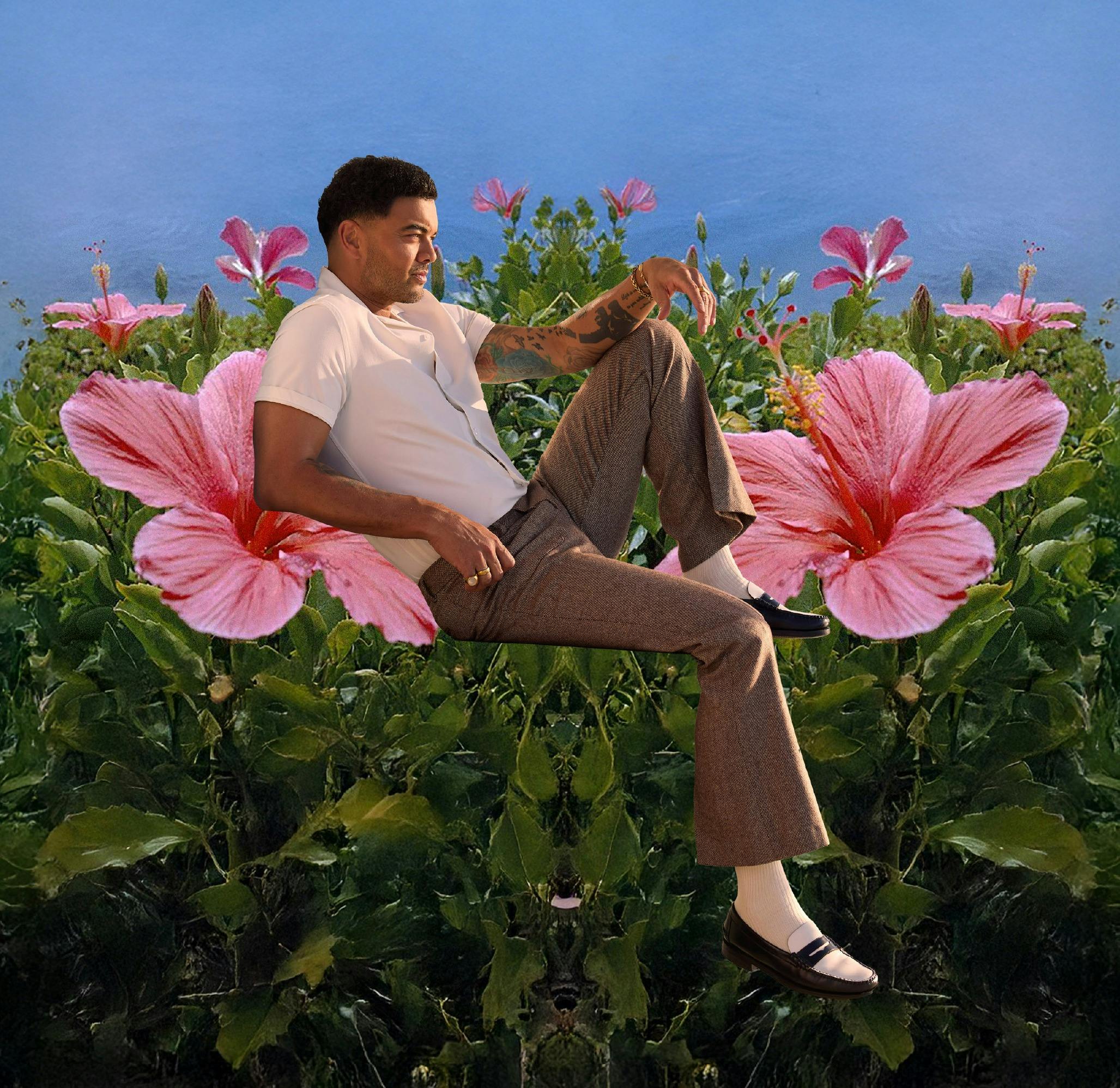 A man sitting on top of plants with large pink flowers.