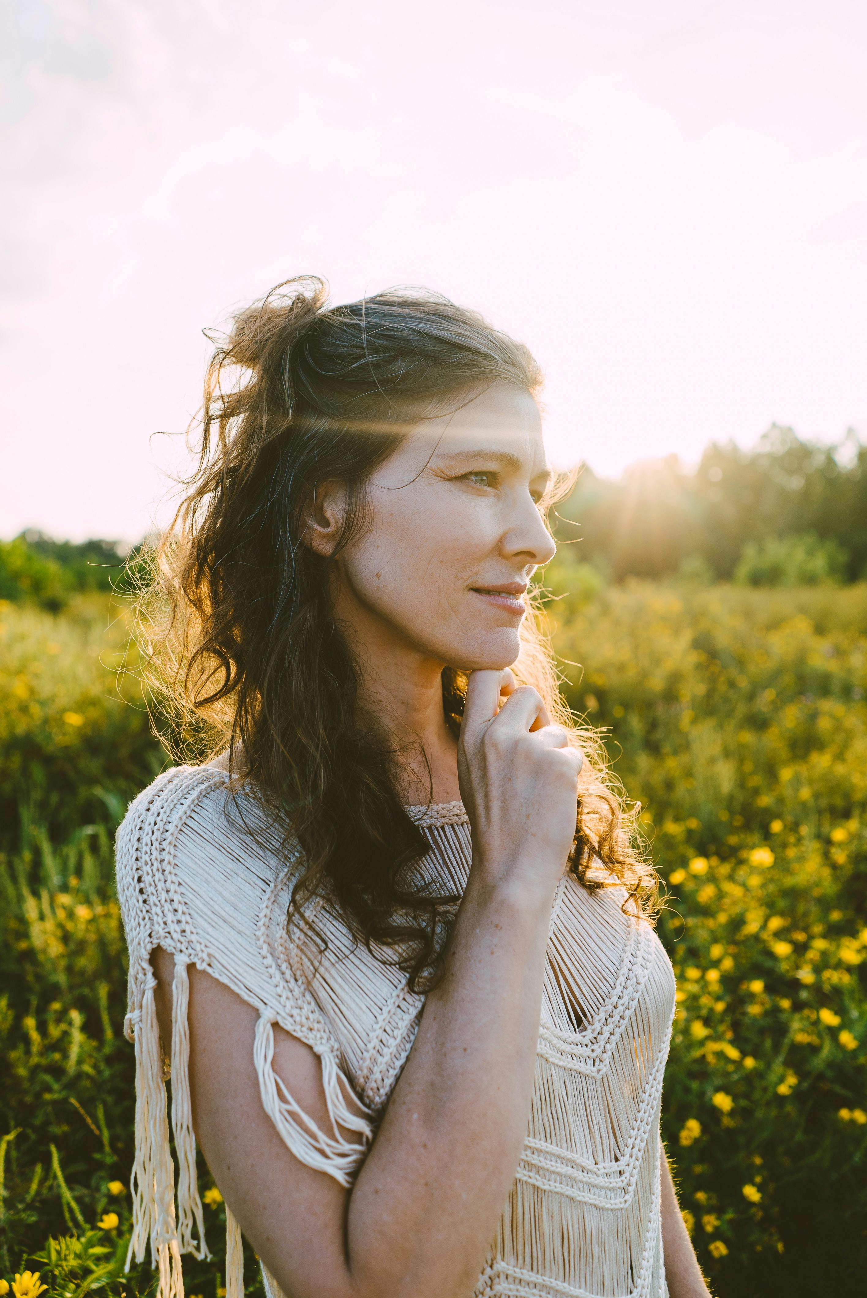 Ruth Moody standing in a meadow with her chin resting on her finger