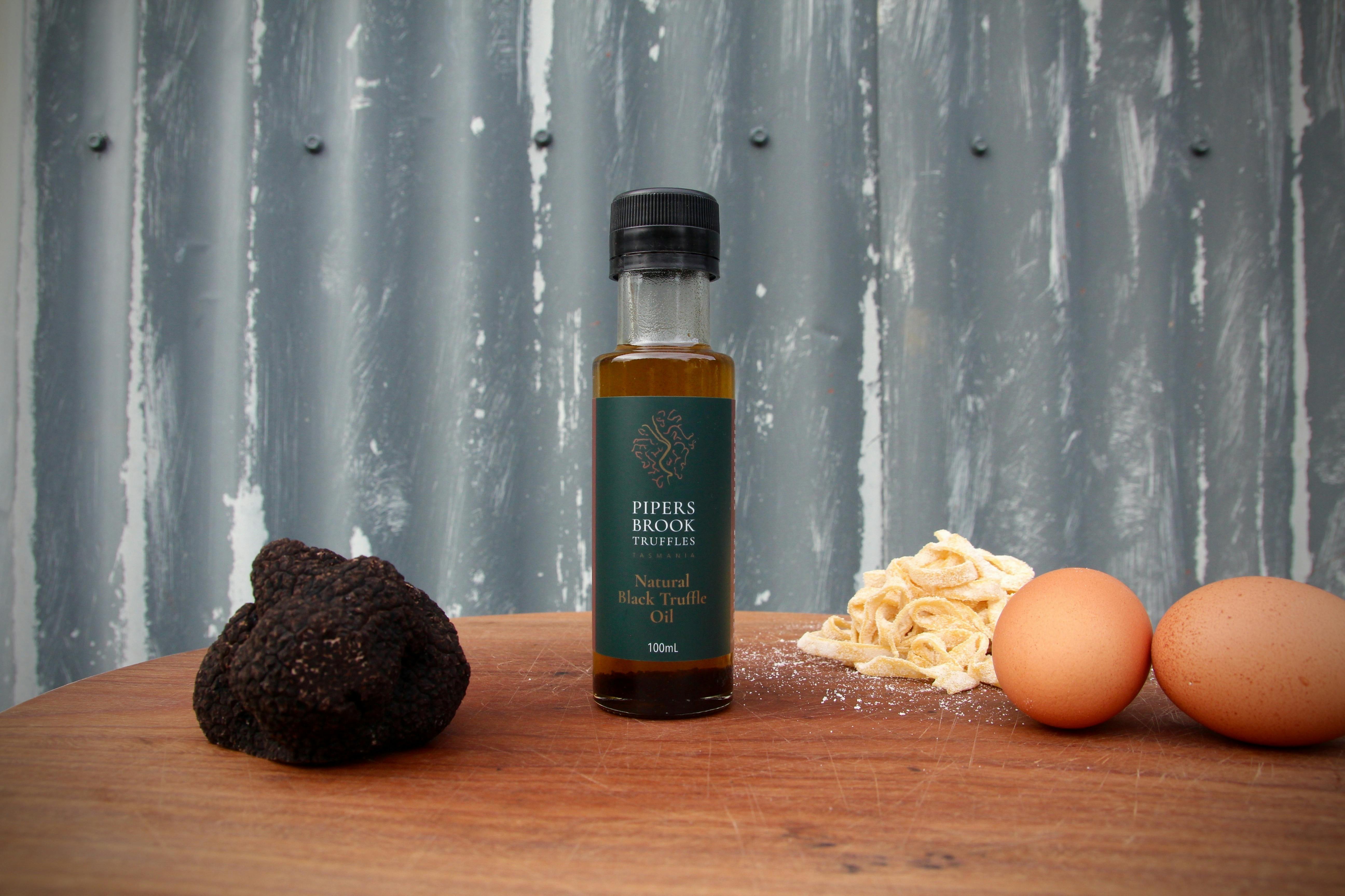 Bottle of truffle oil with a black truffle, egg and pasta in the background