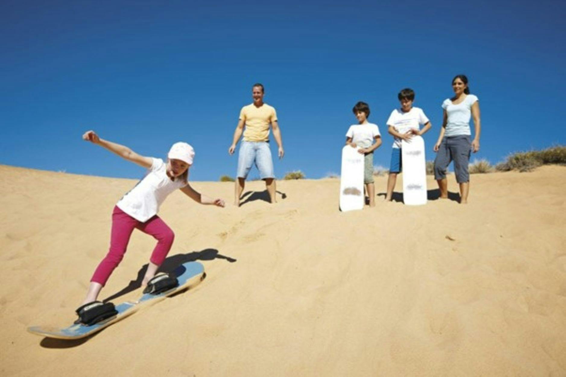 People riding boards on Cunnamulla Sand Dunes