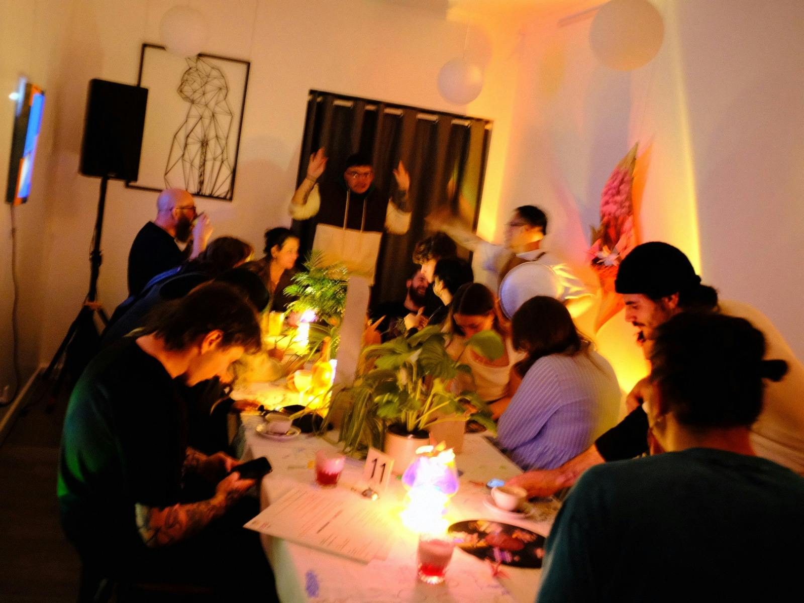 Everyone sitting at communal table enjoying art and cocktails