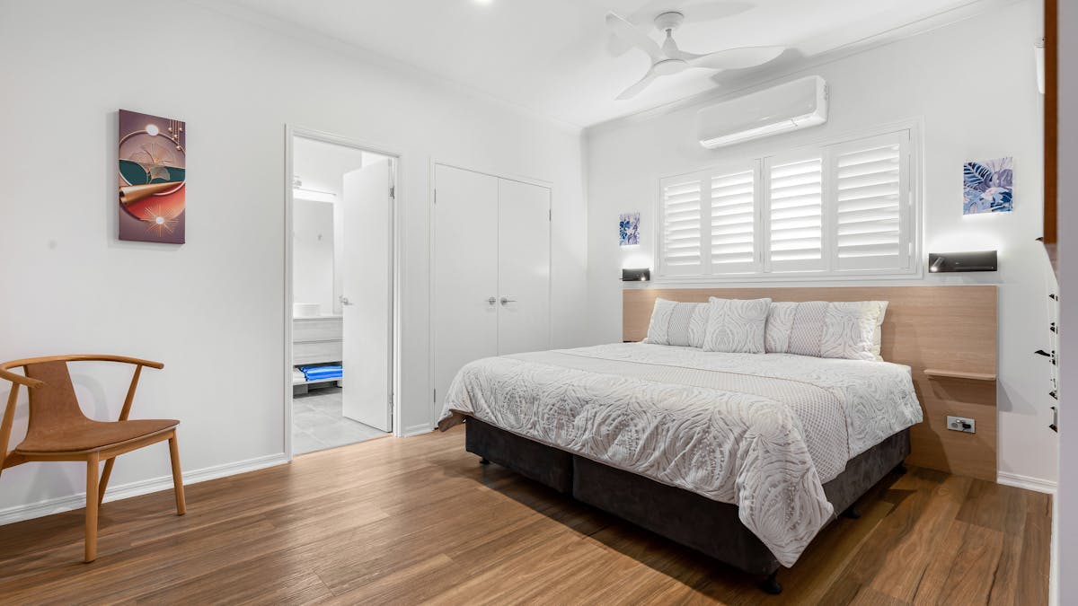 Image of King Size Bed with white shutters on windows and glipse into ensuite