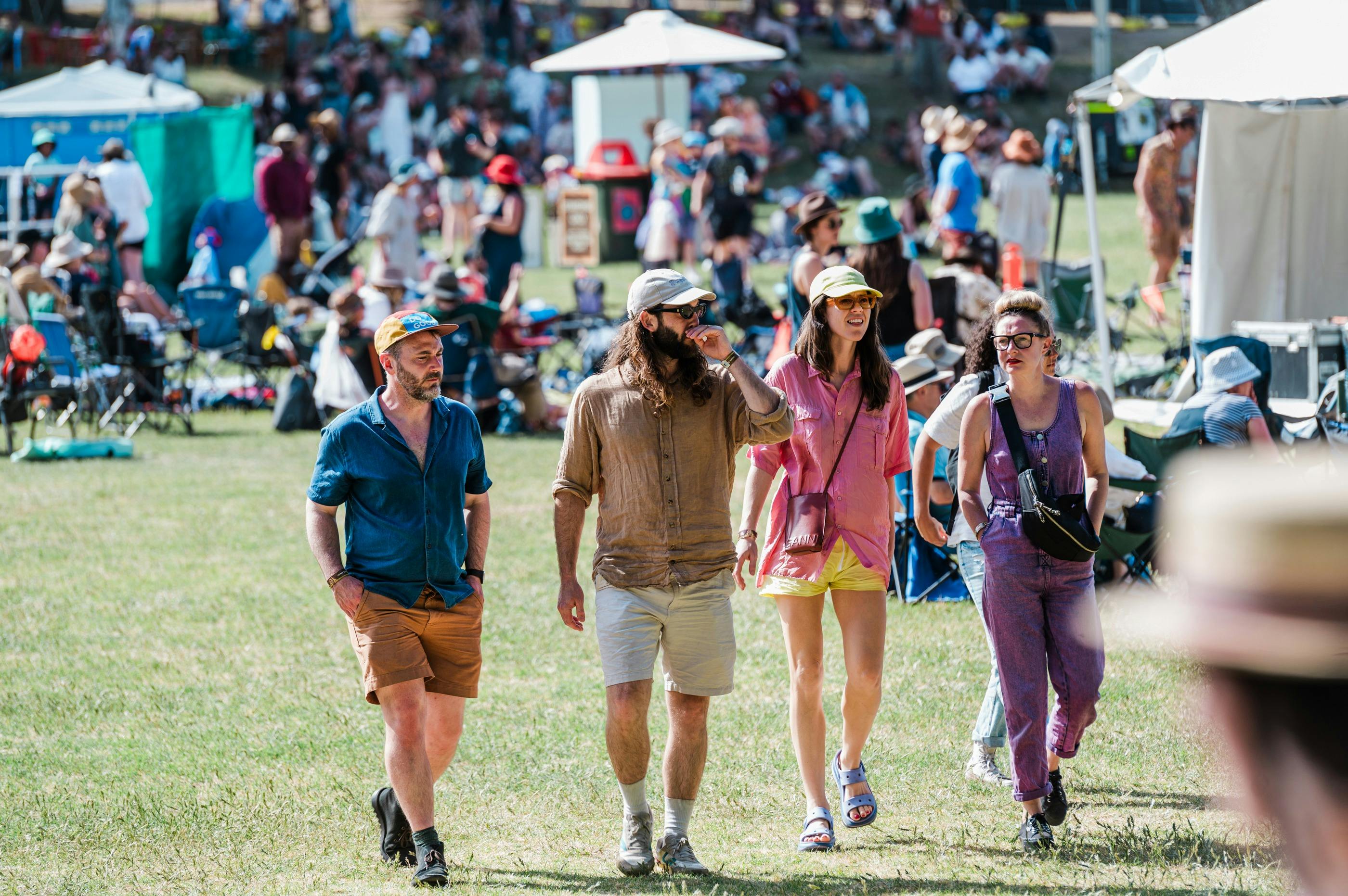 A group of four festival punters walk through the crowd on the Sunken Oval.