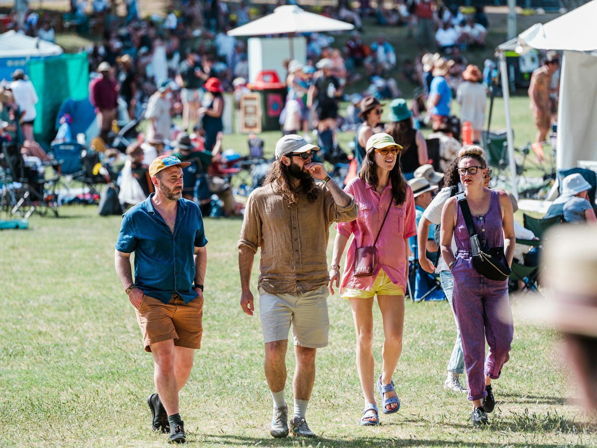 A group of four festival punters walk through the crowd on the Sunken Oval.