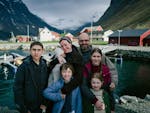 A family poses smiling in front of a Norwegian Fjord