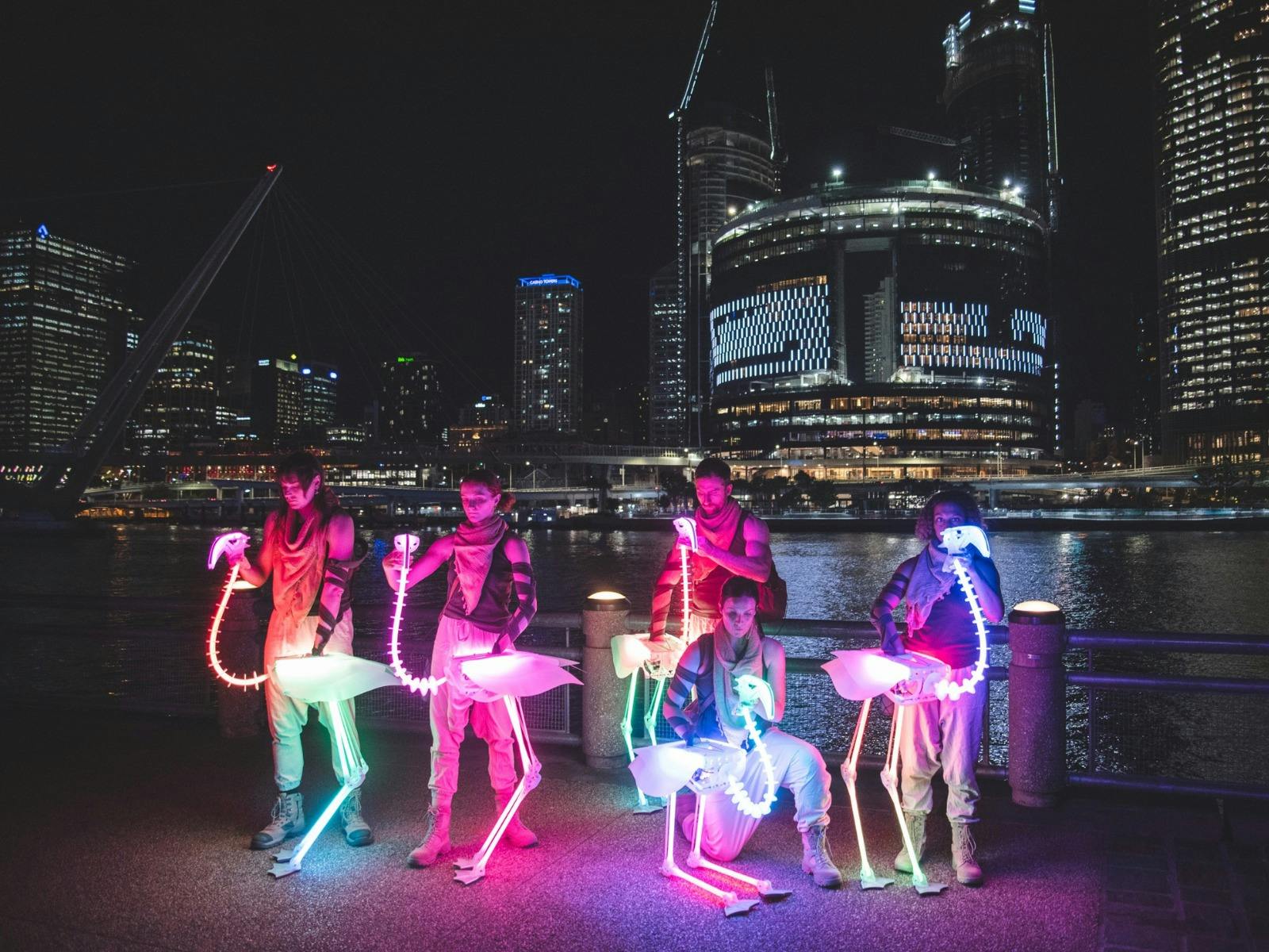 Puppeteers operate rainbow LED flamingo skeletons