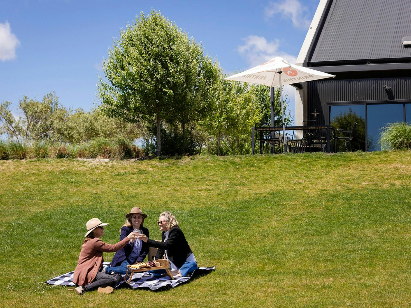 Printhie Wines Picnic witha group of three women sitting on a rug in front of the cellar door