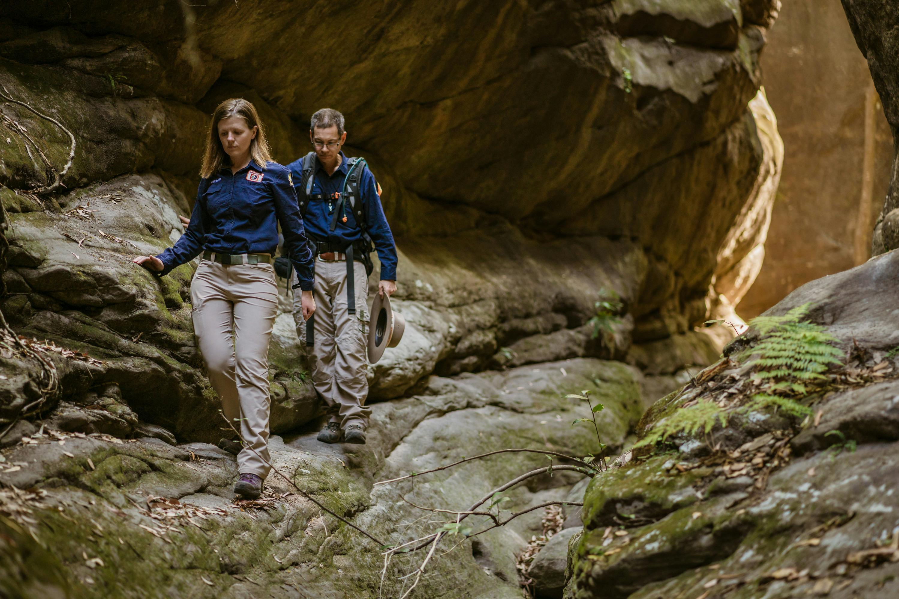 Two tour guides walk through a narrow side gorge at Carnarvon Gorge.