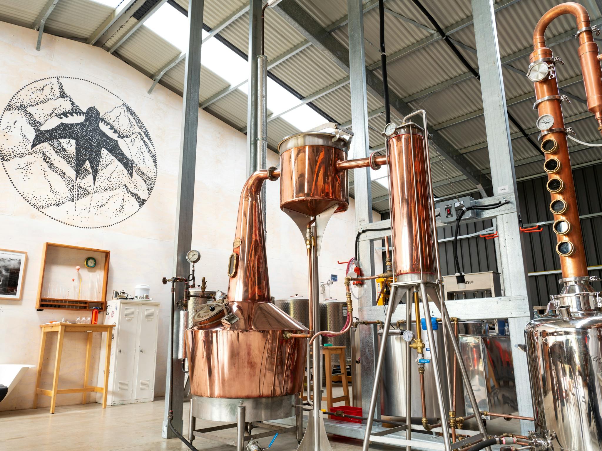 A view of the inside of Swiftcrest Distillery showing copper stills and pipework