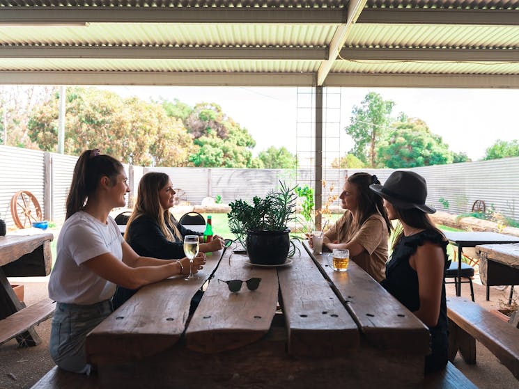 4 girls sitting around a big table in a garden