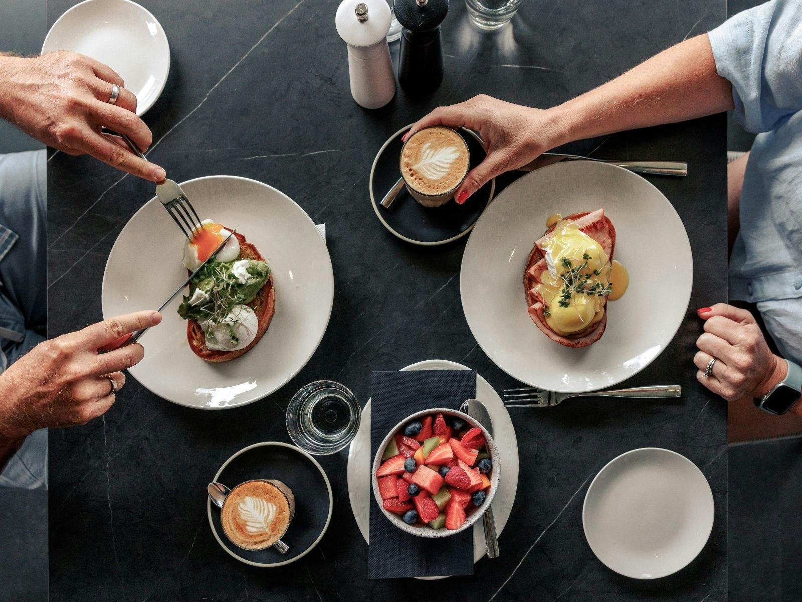 Couple enjoying breakfast of eggs, coffee and fresh fruit in hotel dining room
