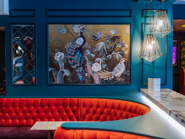 Luxurious red bar booths and blue peacock artwork on wall