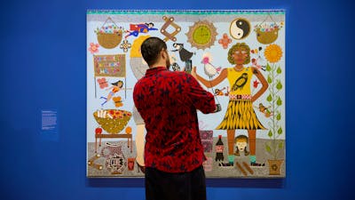 A person in a floral shirt takes a photo of a colourful portrait of Kaylene Whiskey and Dolly Parton
