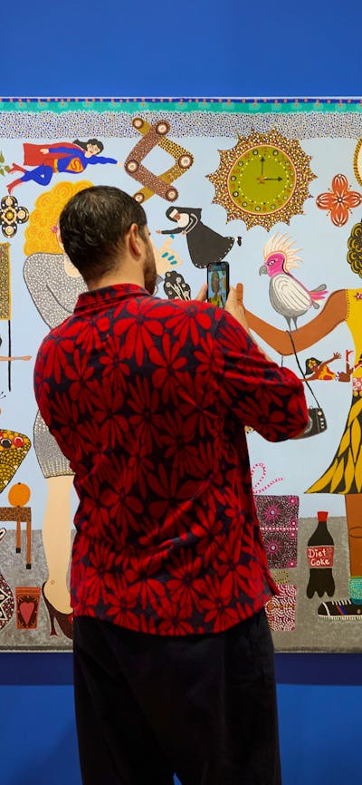 A person in a floral shirt takes a photo of a colourful portrait of Kaylene Whiskey and Dolly Parton