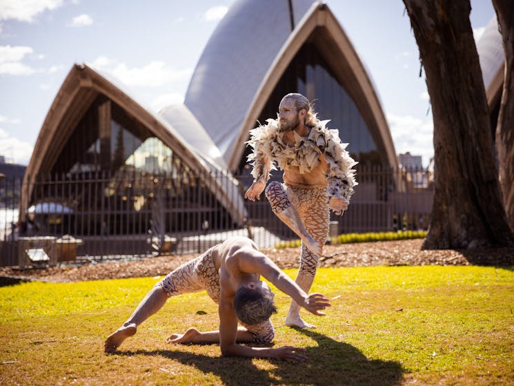 Two male dancers pose on the grass outside Sydney Opera House