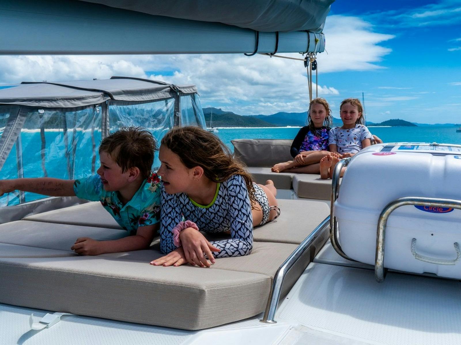 Kids sitting on the sun bed of a boat