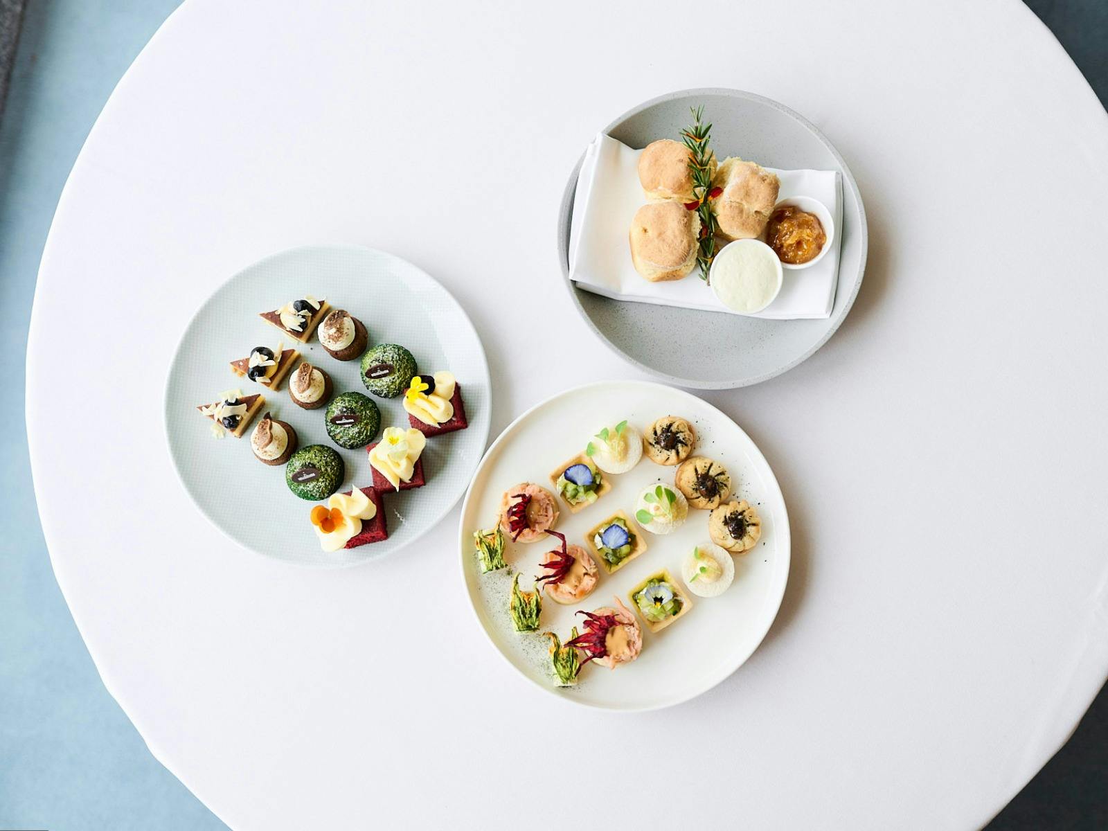 Birds eye view of three high tea plates featuing scones, cakes and small goods