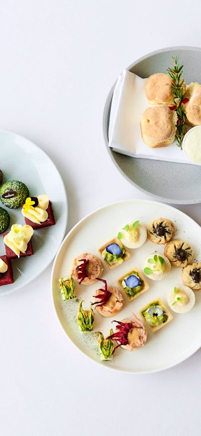 Birds eye view of three high tea plates featuing scones, cakes and small goods