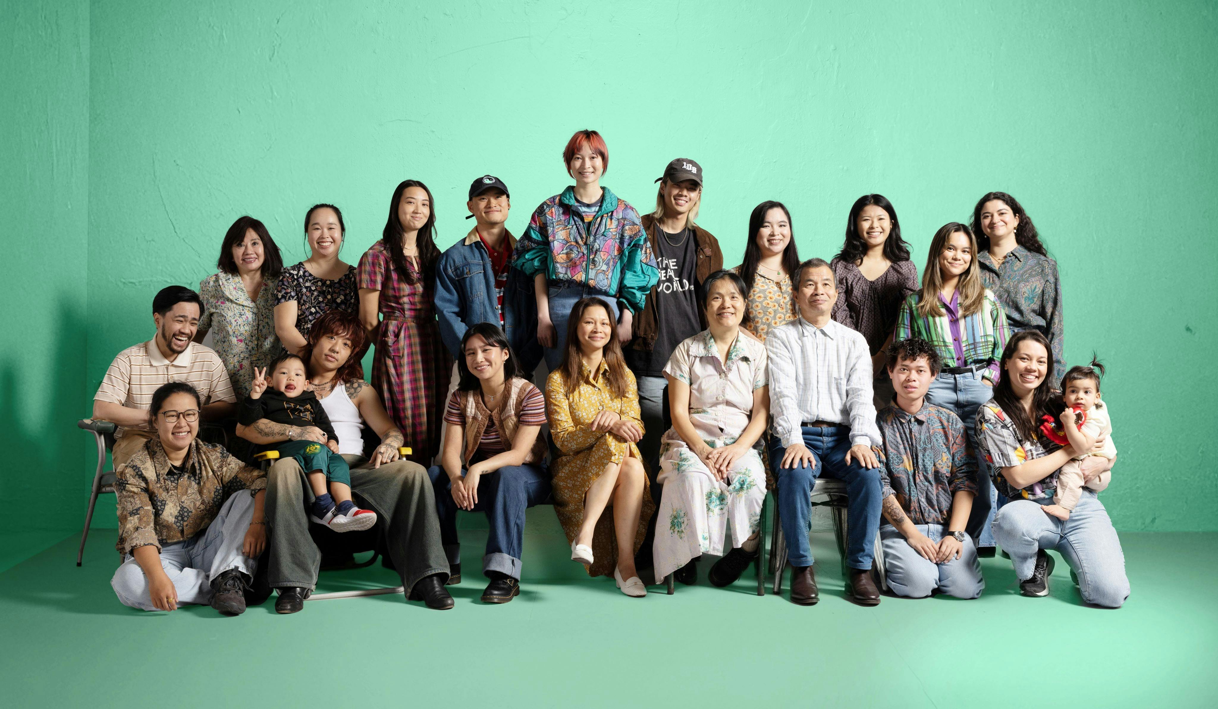 Very big cheerful group portrait of Vietnamese family and friends against a green background