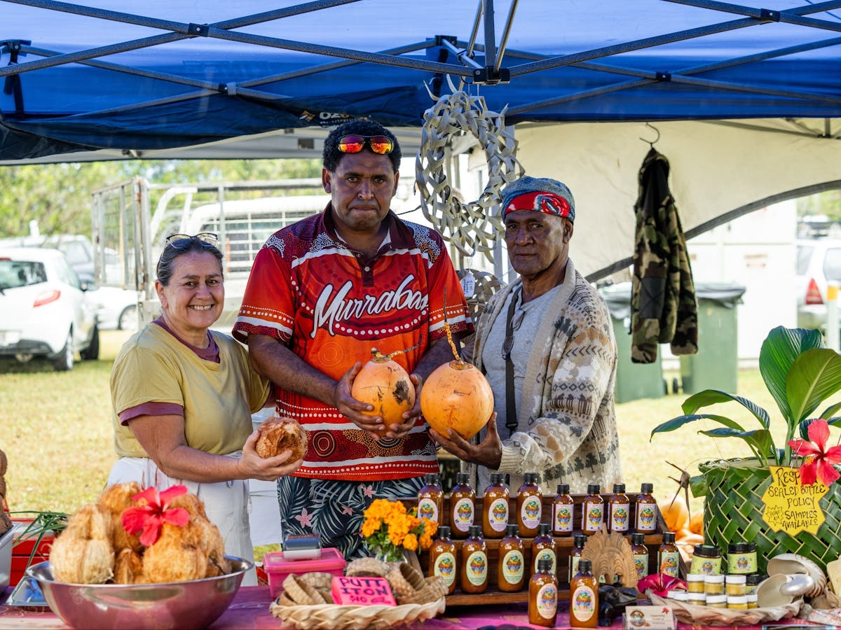 People stand at their stall of natural products holding coconuts at the Mareeba Multicultural Fest.