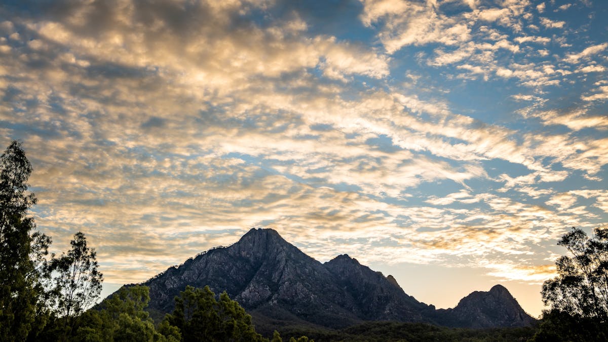 Mountain range silhouetted against a cloudy sky at sunset