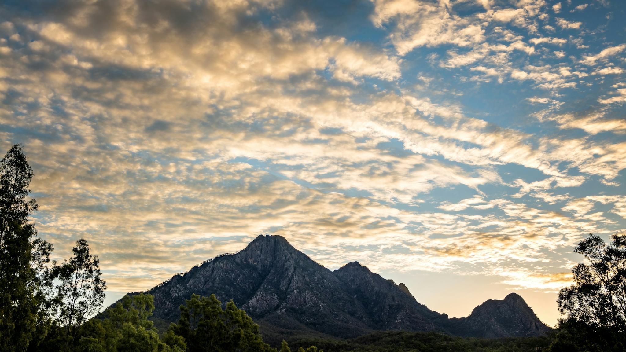 Mountain range silhouetted against a cloudy sky at sunset Mountain range silhouetted against a cloudy sky at sunset
