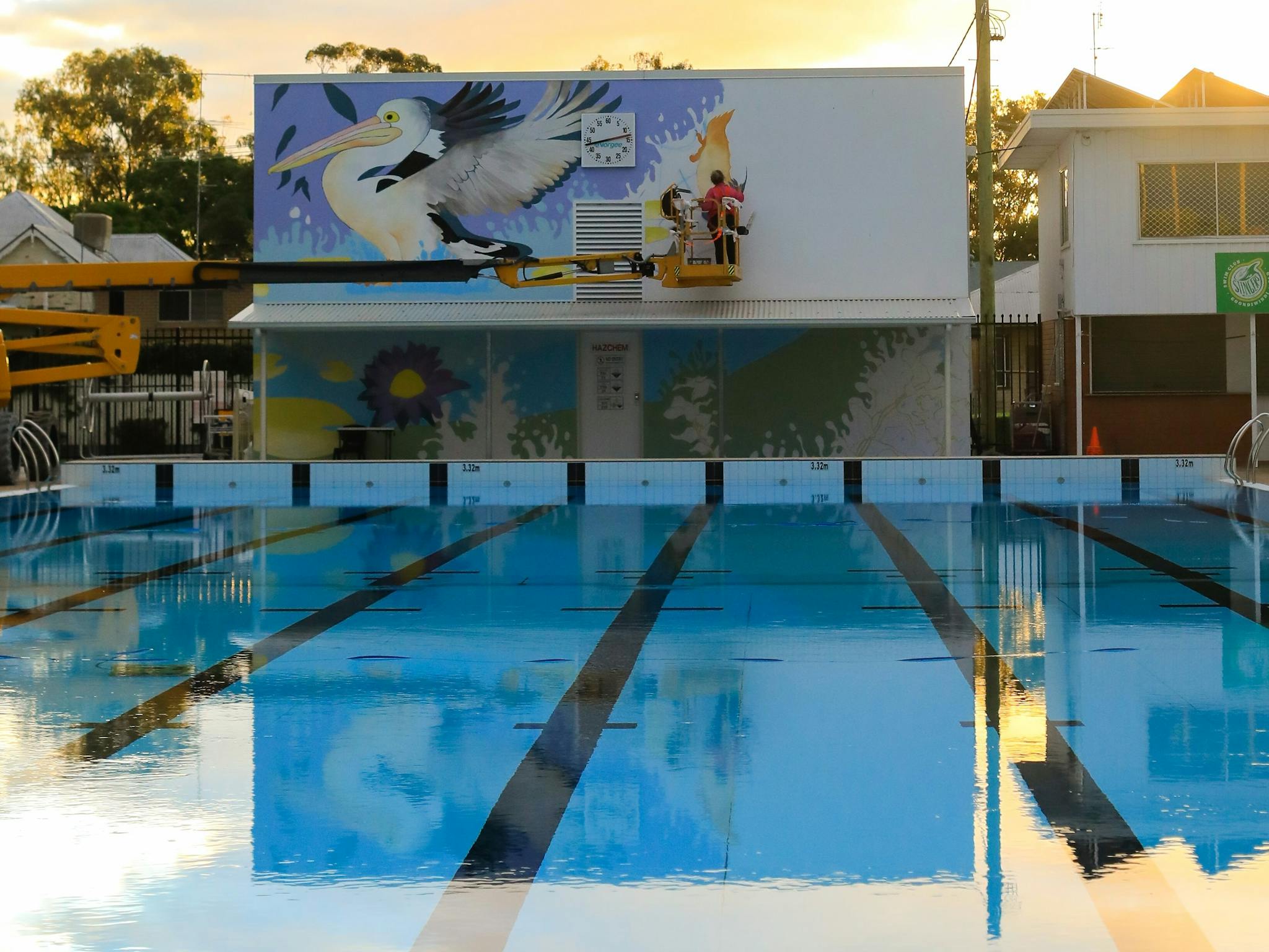 Tia Carrigan on a scissor lift painting a mural on a wall at the Goondiwindi Pool Tia Carrigan on a scissor lift painting a mural on a wall at the Goondiwindi Pool