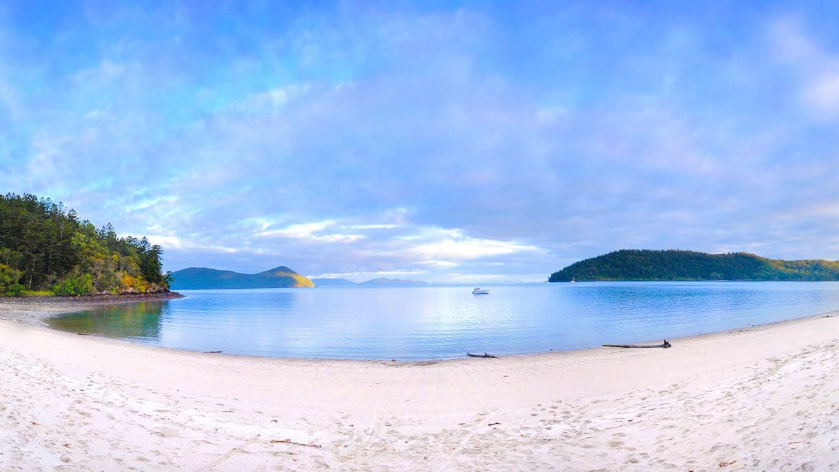 Beach looking out over a bay with islands and a boat in the background. Beach looking out over a bay with islands and a boat in the background.