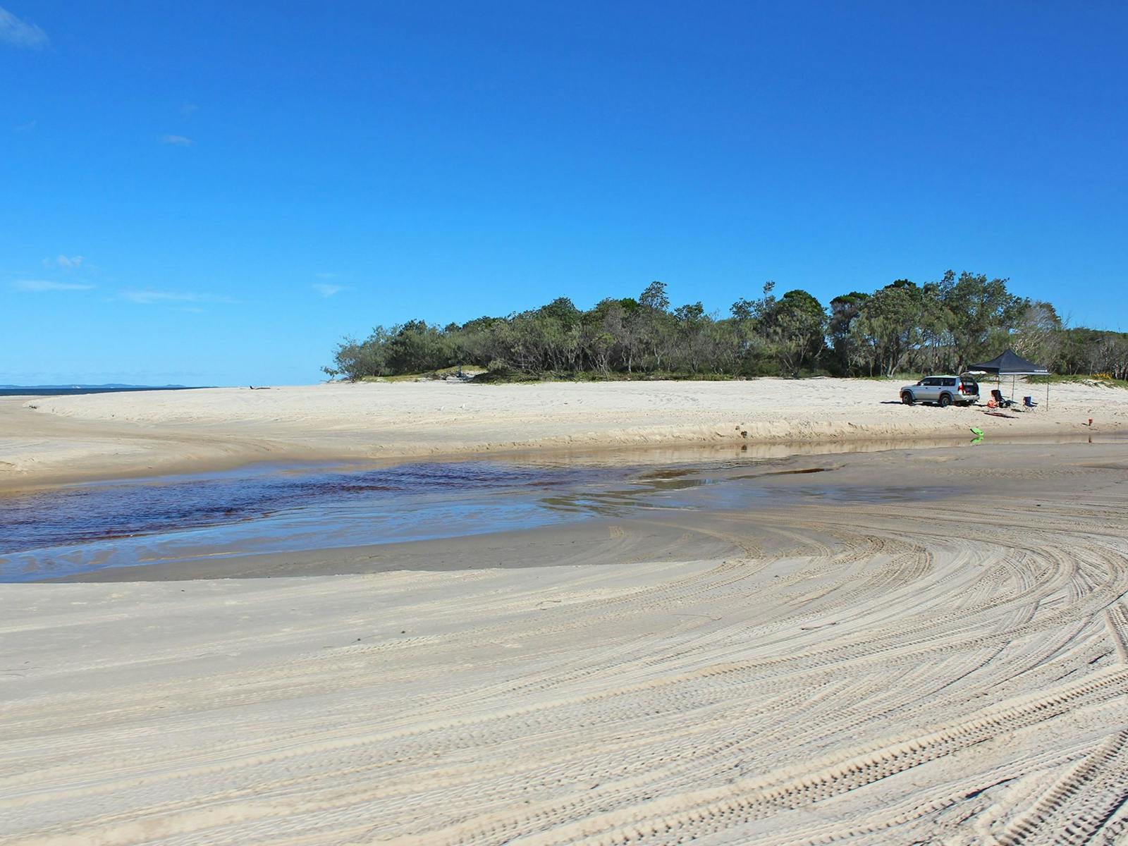 Four-wheel-drive vehicle parked next to a pop up marquee on the beach.