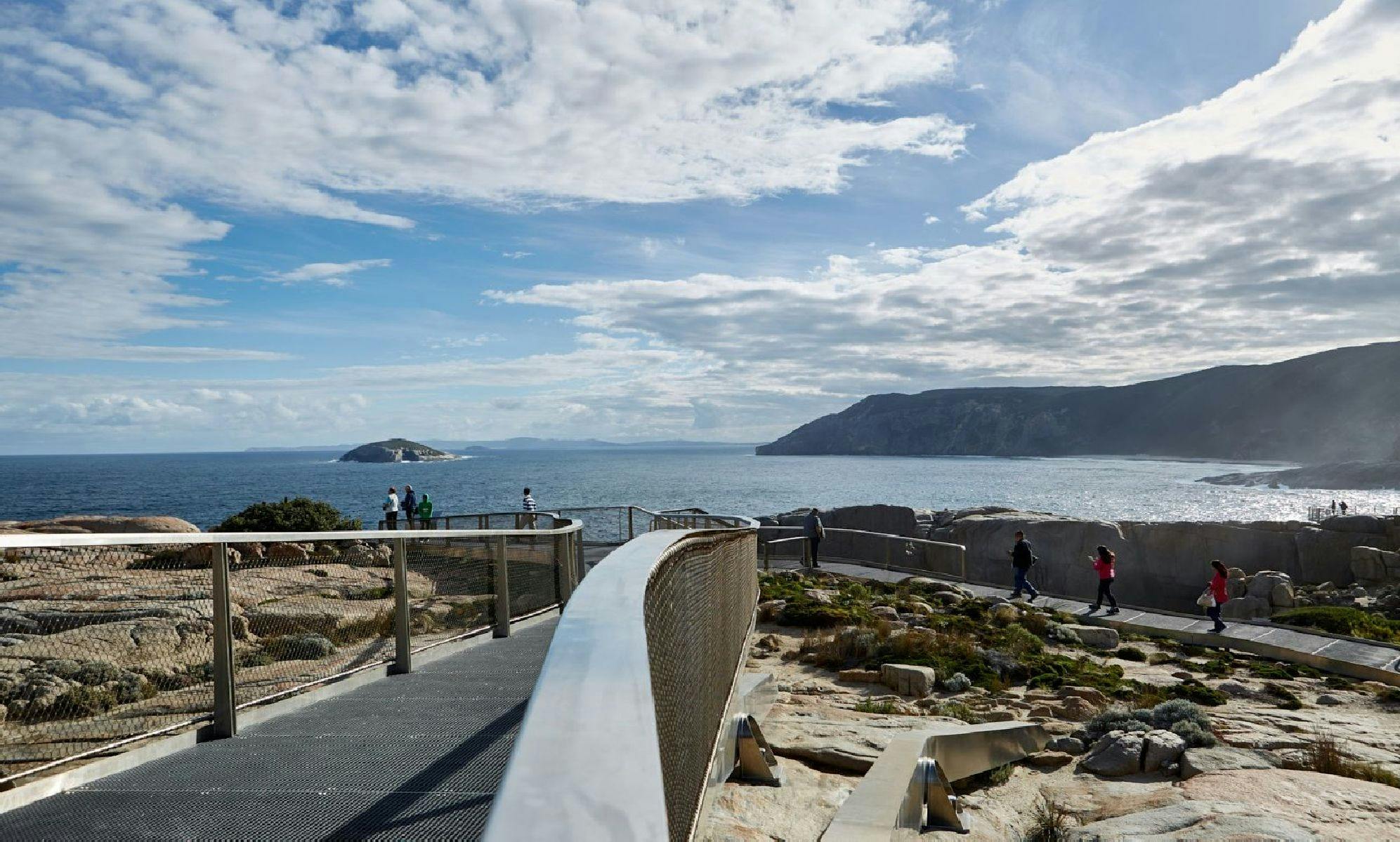 fenced walkway overlooking ocean with island in middle distance