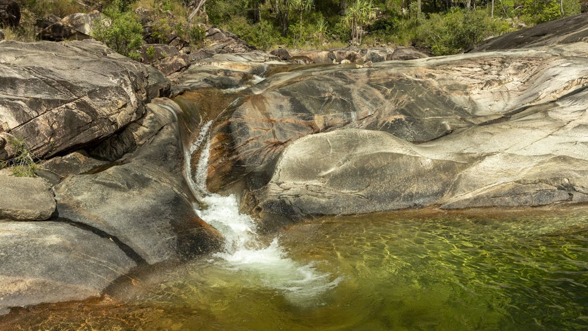 Rockslide with water flowing down it into a rockpool.