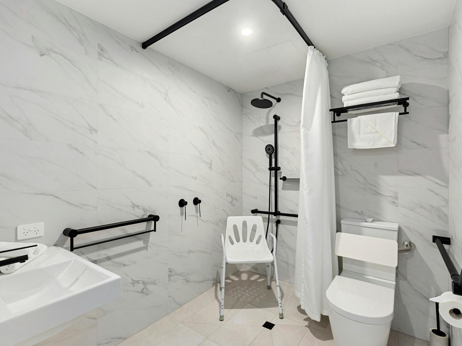 Bathroom showing special accessible features including shower, toilet and hand rails