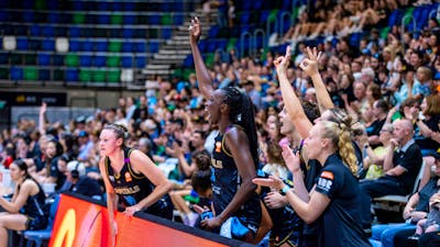 UC Capitals players cheering with their hands up on the player bench.