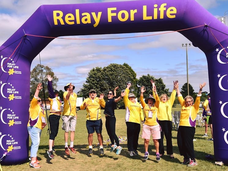 A group of people jumping under a sign which says 'Relay for Life'
